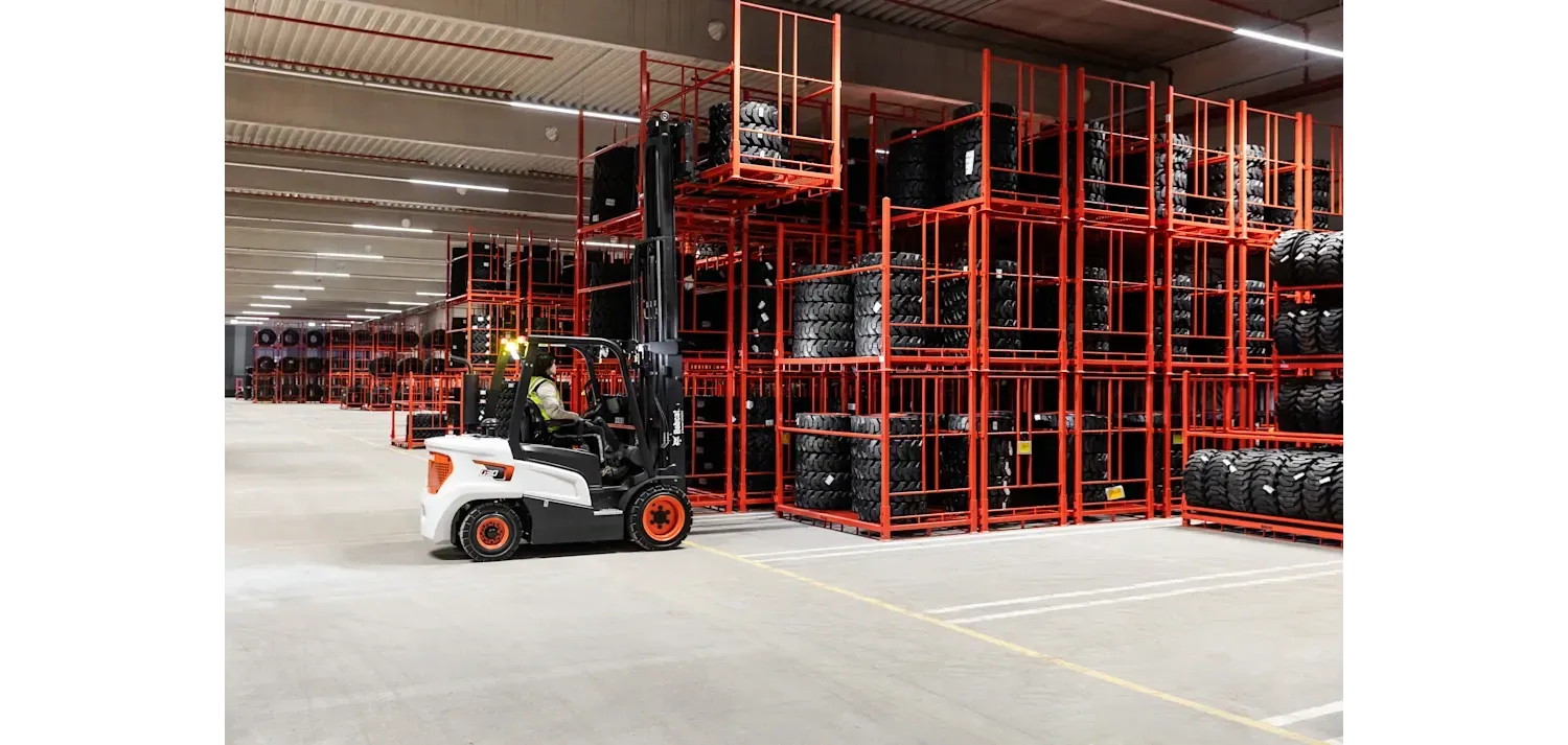A forklift is moving tires in a large warehouse.