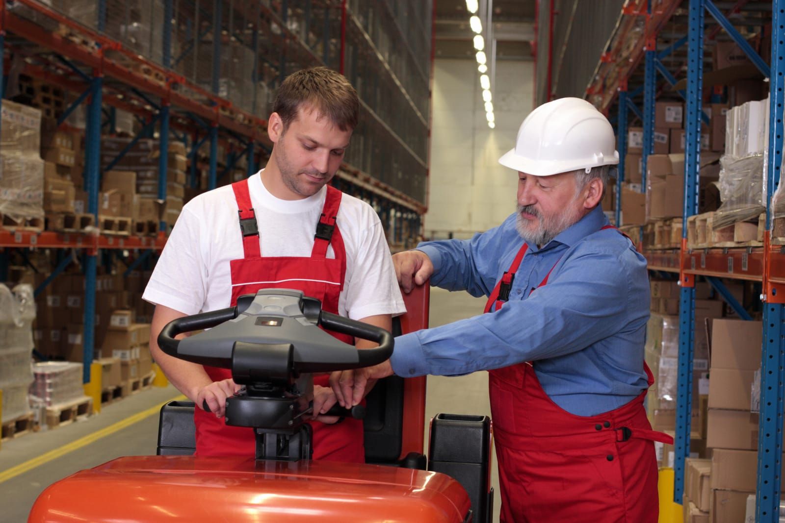 Forklift instructor explaining safety regulations to operators during a warehouse training session