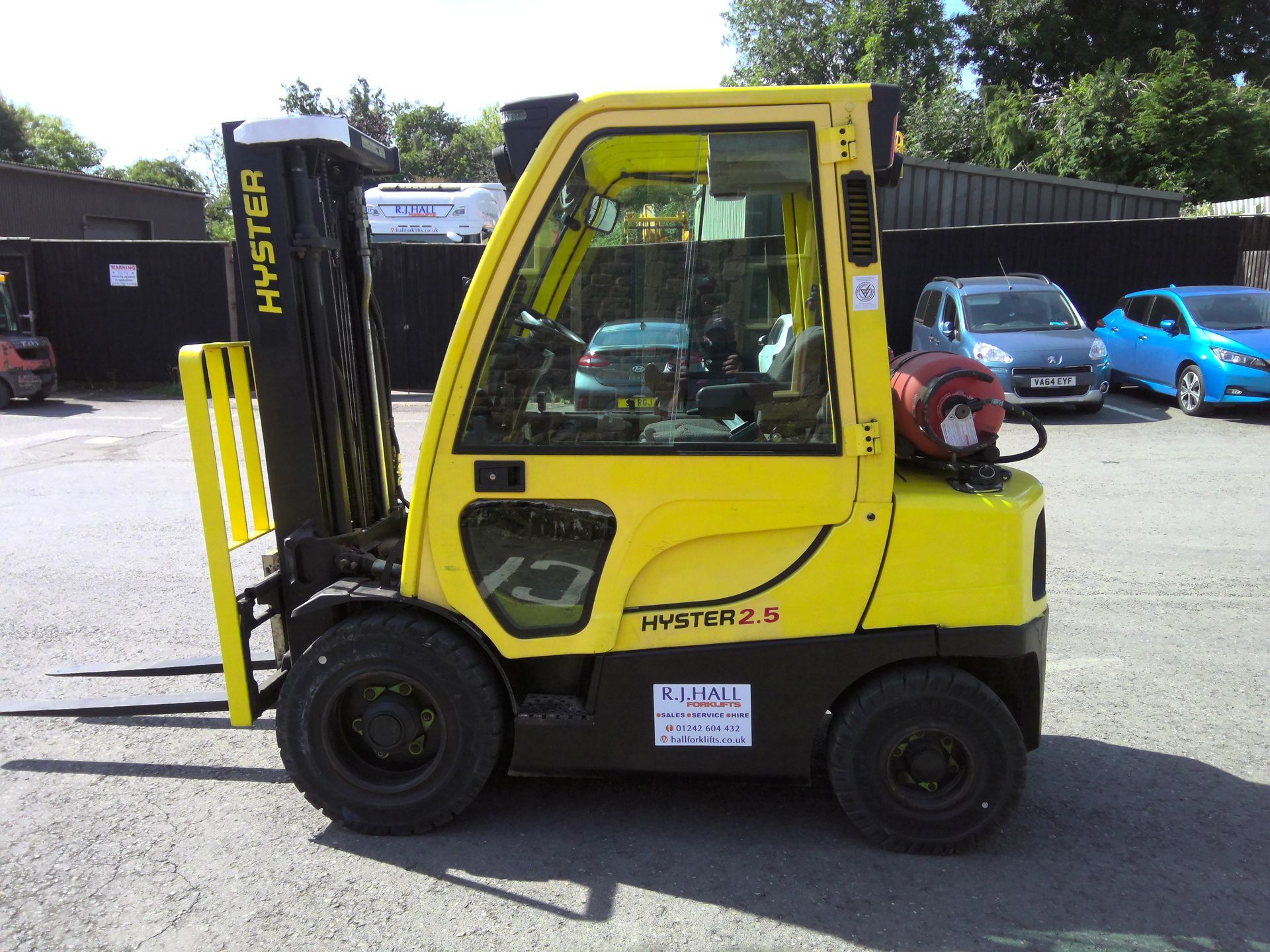 A yellow hyster forklift is parked in front of a building