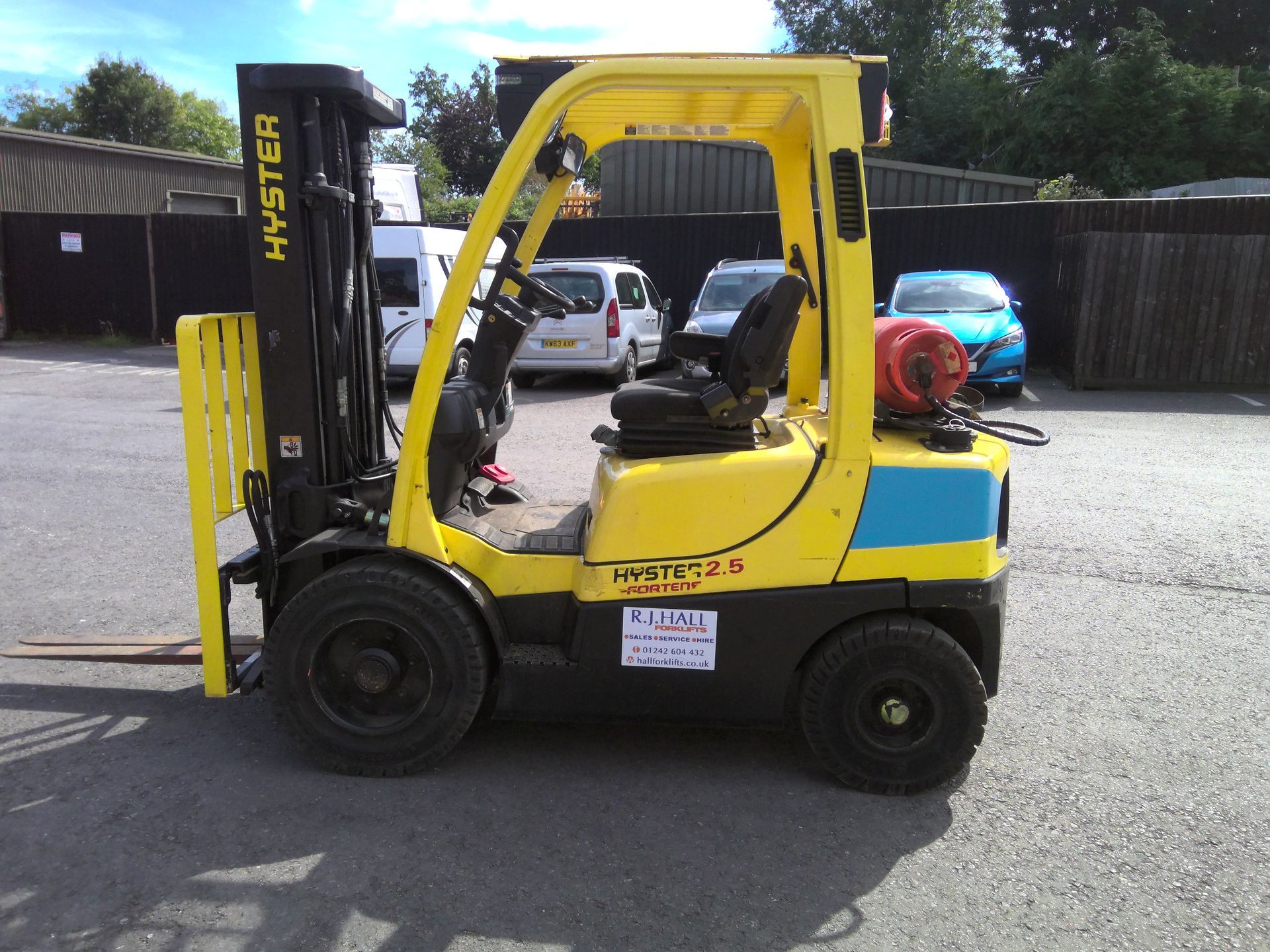 A yellow hyster forklift is parked in front of a building