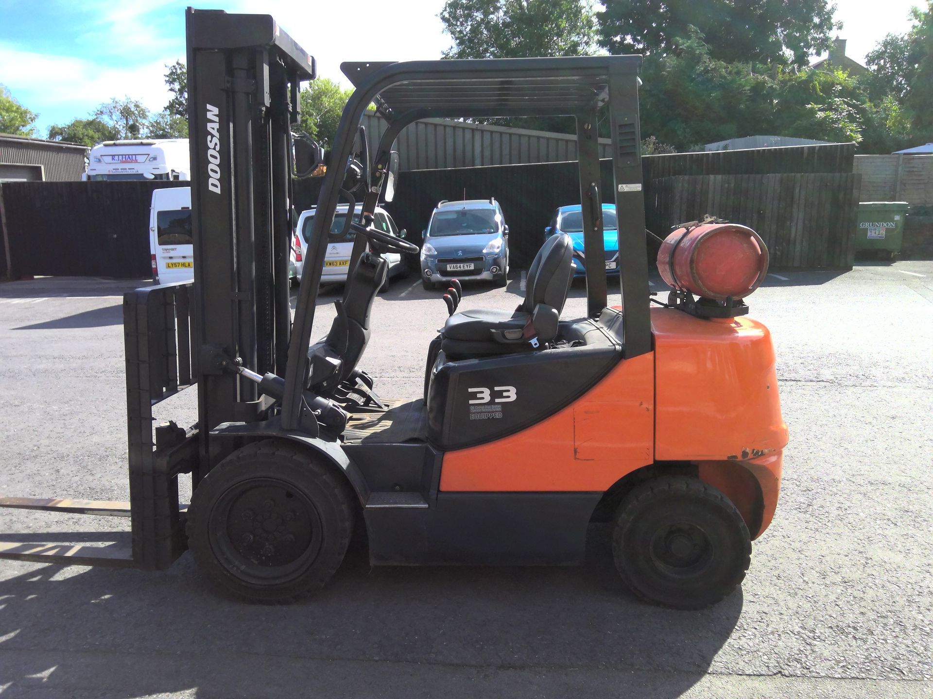 A doosan forklift is parked in front of a brick building