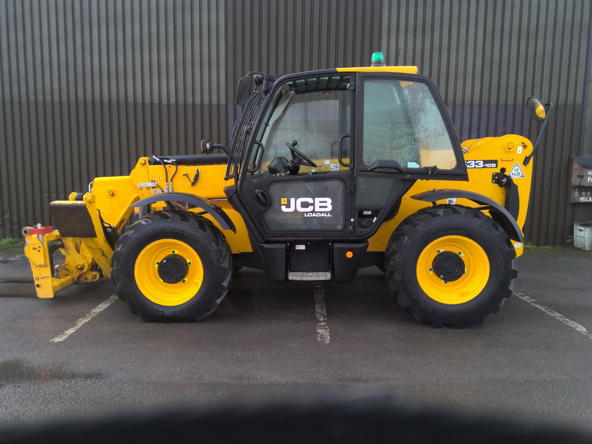 A yellow jcb tractor is parked in a parking lot