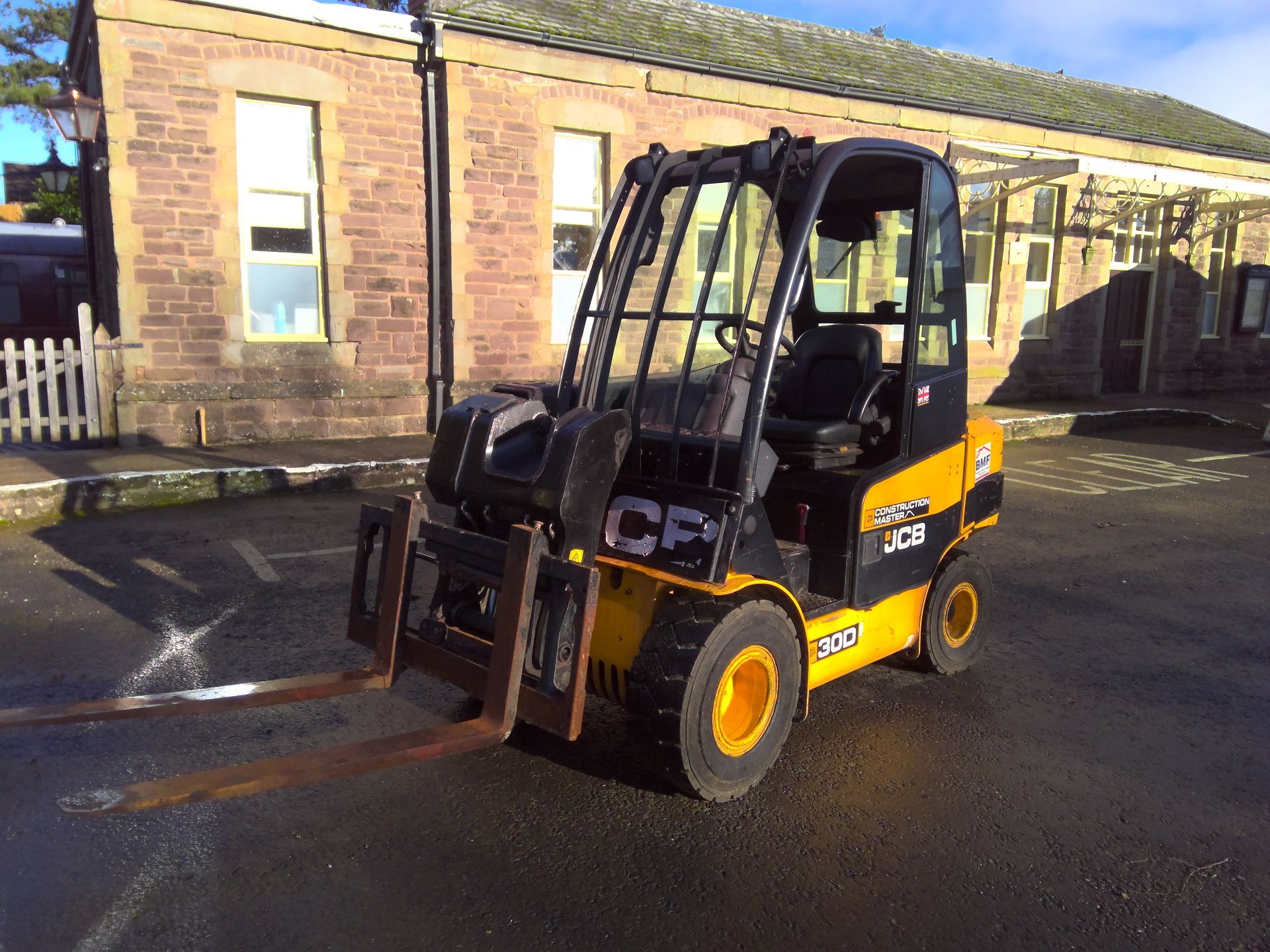 A jcb forklift is parked in front of a brick building