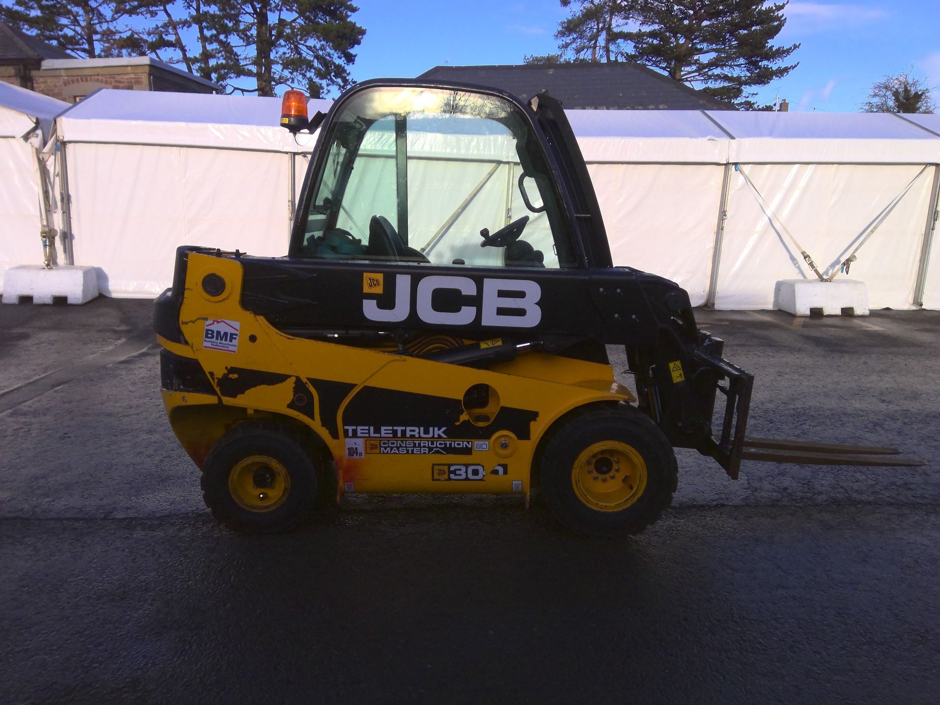 A yellow jcb forklift is parked in a parking lot