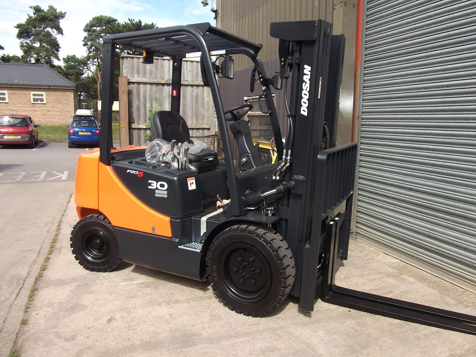 An orange and black forklift is parked in front of a building