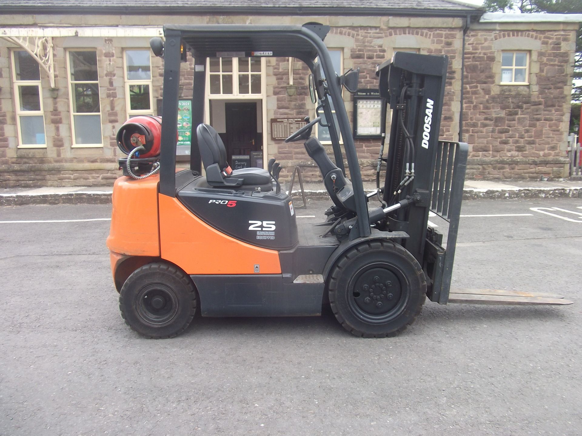 A doosan forklift is parked in front of a building