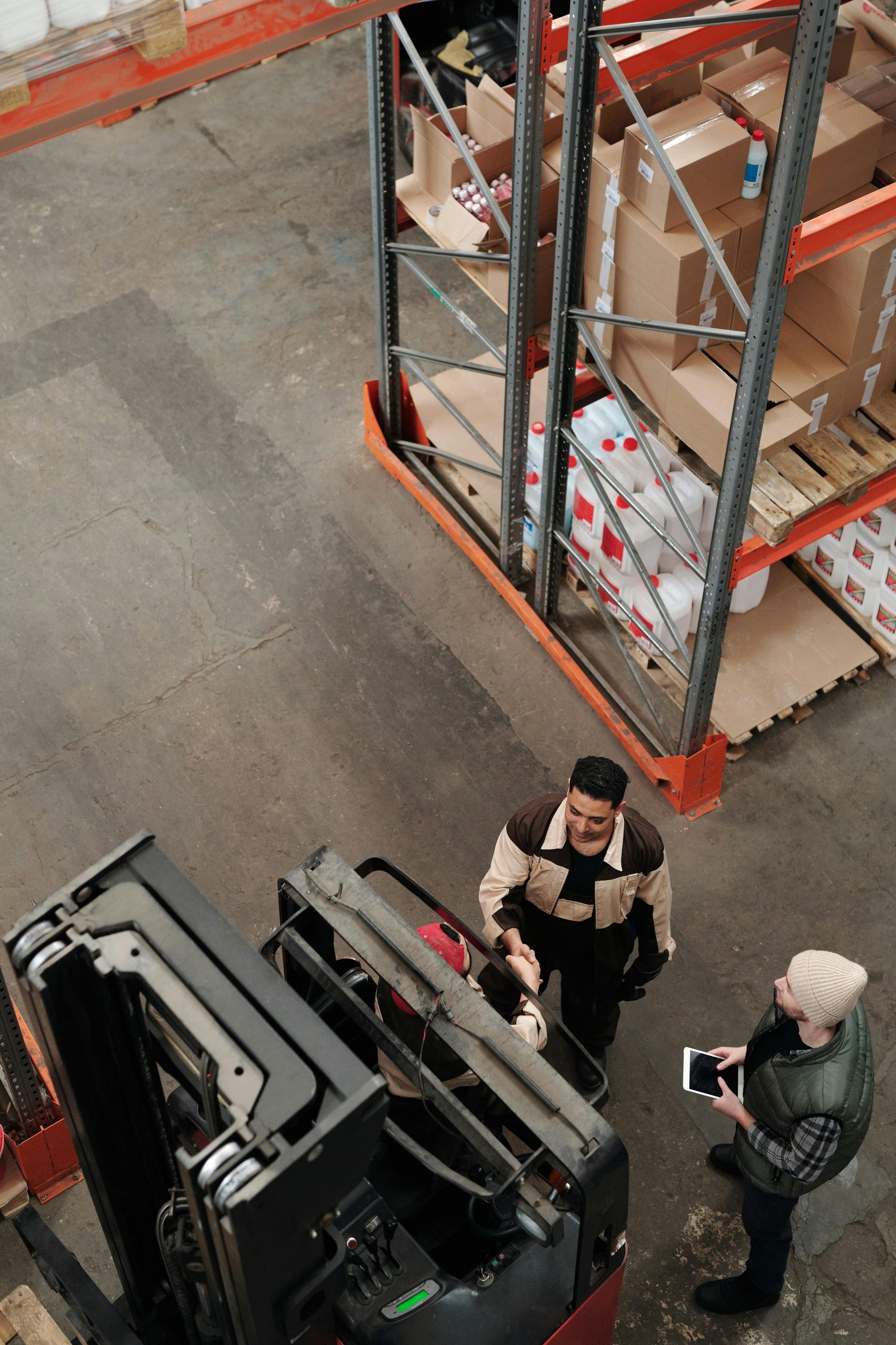 Forklift technician discussing a planned maintenance report with a warehouse manager, highlighting cost control and equipment safety in a UK warehouse setting