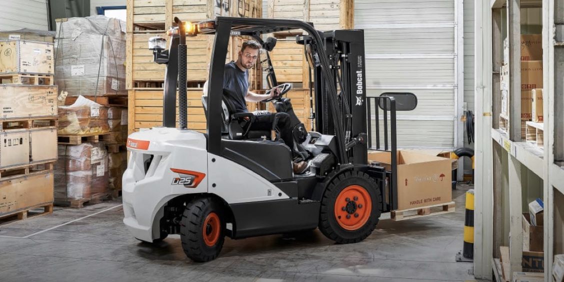 A man is driving a forklift in a warehouse.