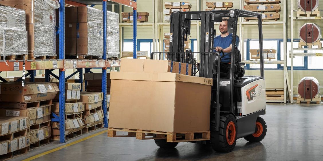 A man is driving a forklift in a warehouse.