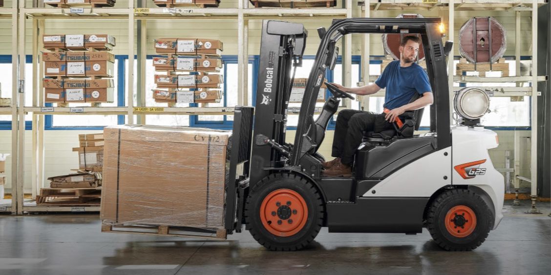 A man is driving a forklift in a warehouse.