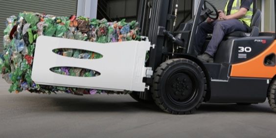 A forklift is carrying a large pile of plastic bottles.