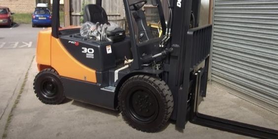 A forklift is parked in front of a garage door.