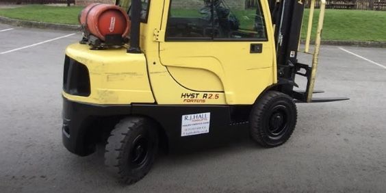 A yellow forklift is parked in a parking lot.