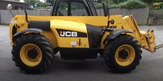 A yellow jcb tractor is parked in a parking lot