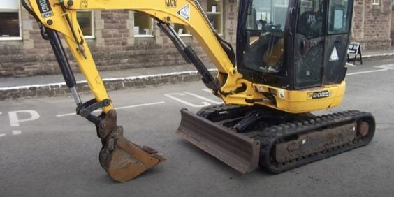 A small yellow excavator is parked on the side of the road.