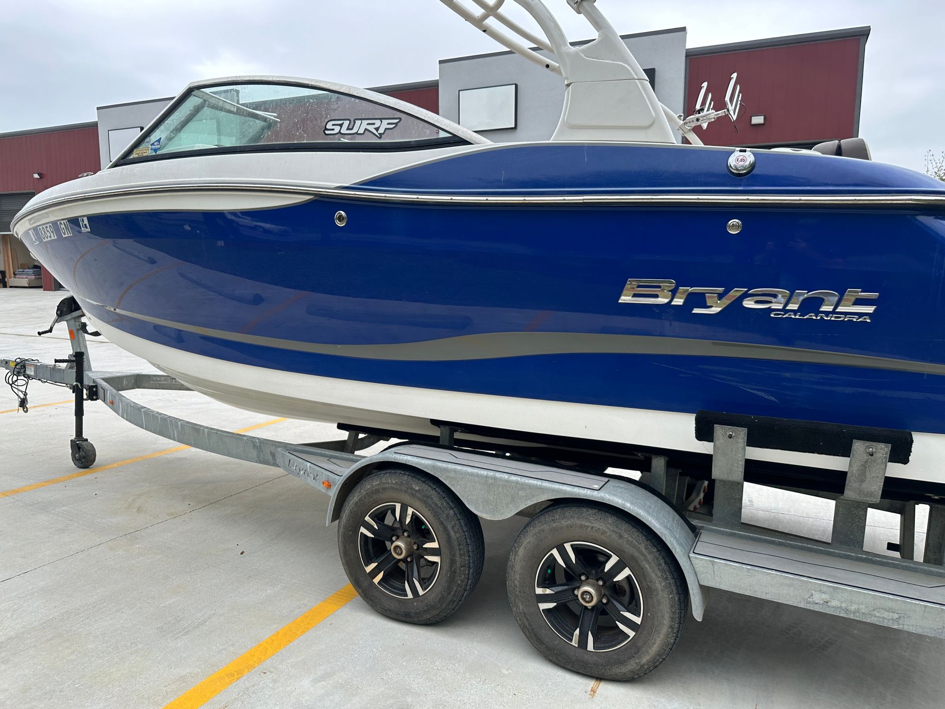 Blue Bryant boat on a trailer in a parking lot, shown from the side.