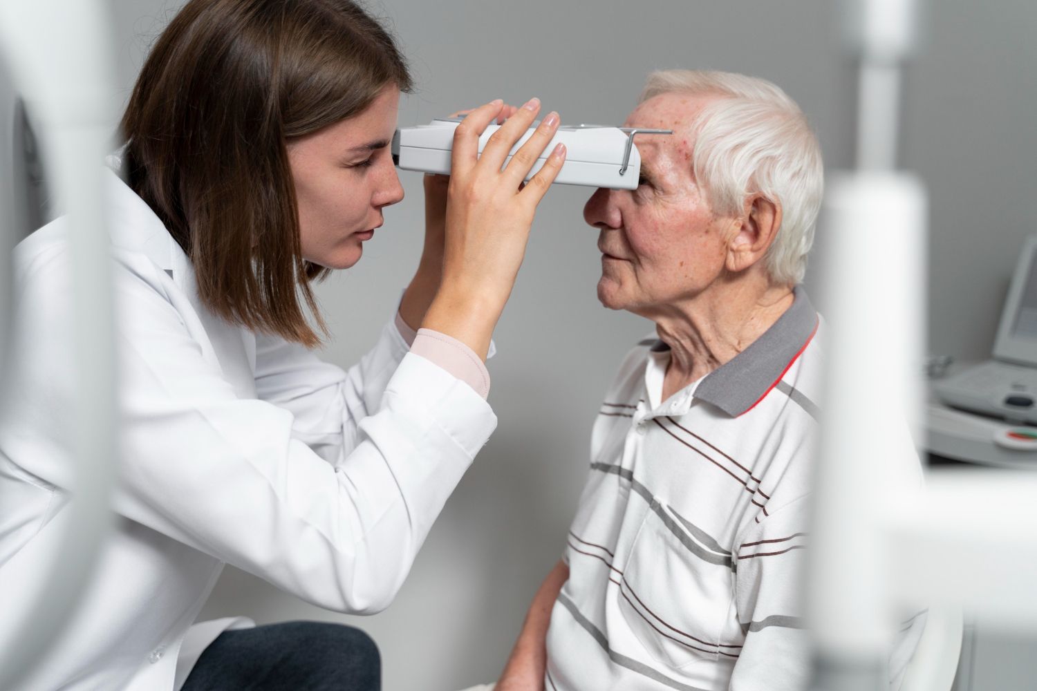 A female doctor is examining an elderly man 's eye.