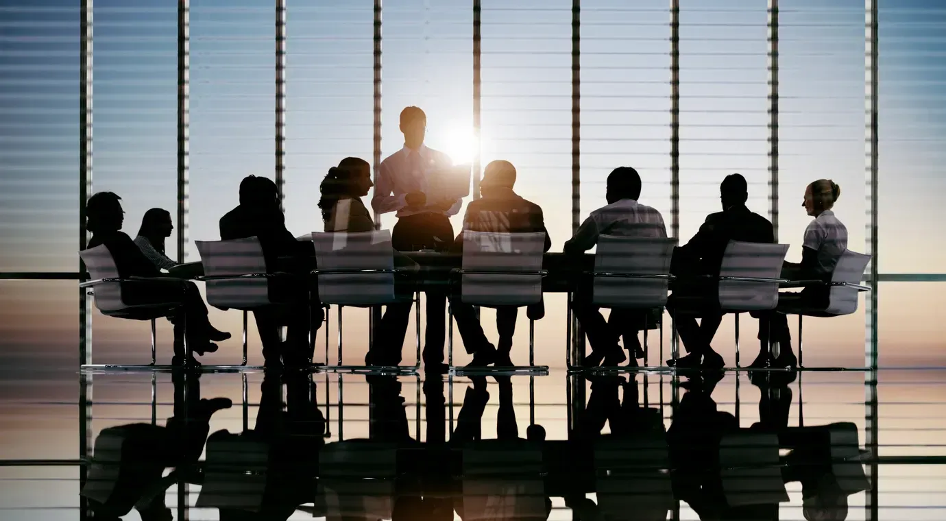 A group of people are sitting around a table in a conference room.