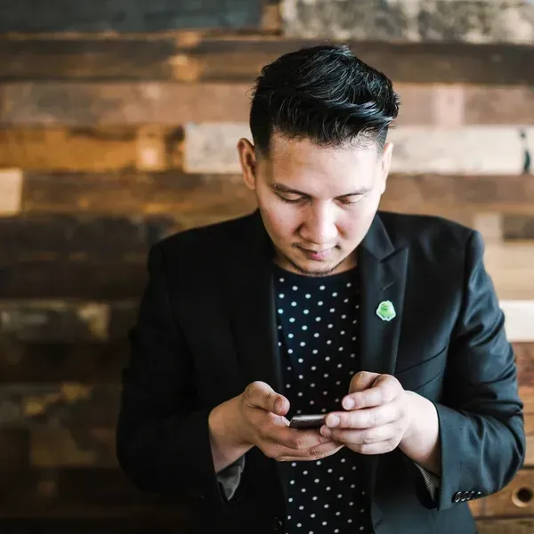 A man in a suit is looking at his cell phone