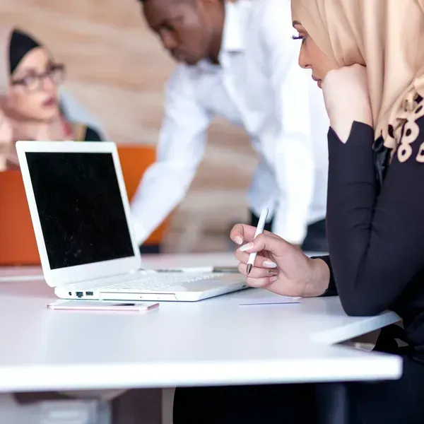 A woman is sitting at a table with a laptop on it