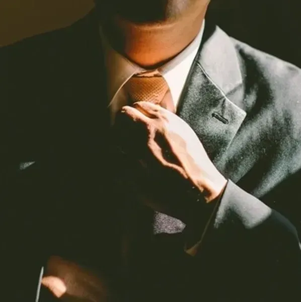 A man in a suit and tie is adjusting his tie