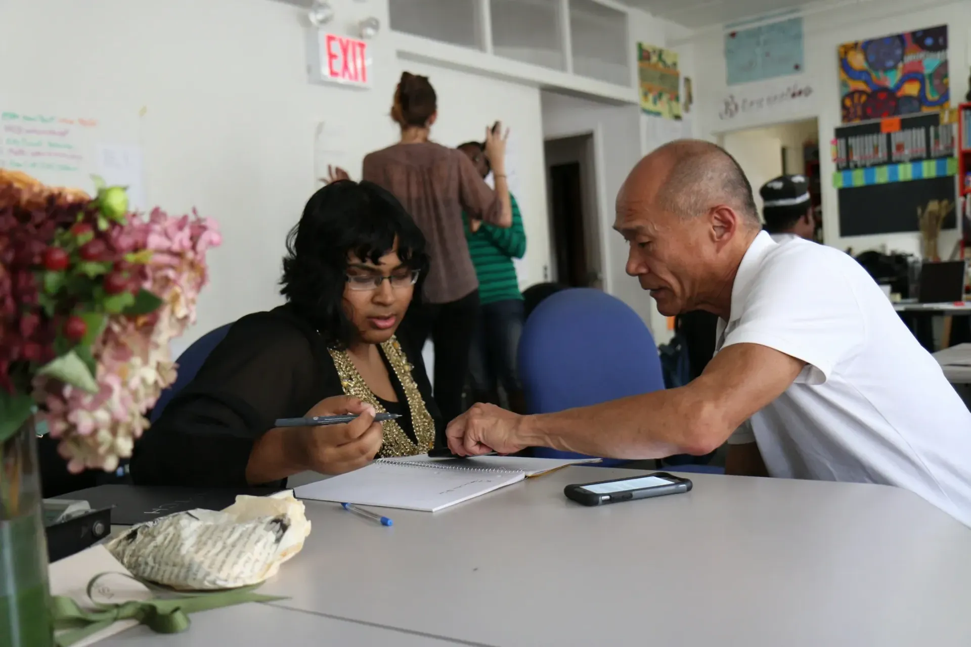 A man and a woman are sitting at a table in front of an exit sign