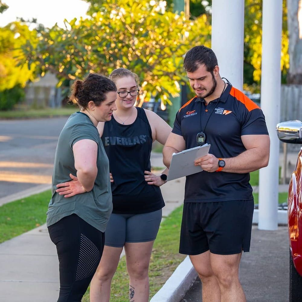 A Man Is Looking At A Tablet While Two Women Look On — Ultimate Results Training in Aitkenvale, QLD