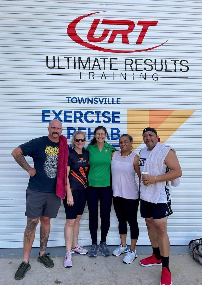 A Group Of Five People Are Posing For A Picture In Front Of A Garage Door — Ultimate Results Training in Aitkenvale, QLD