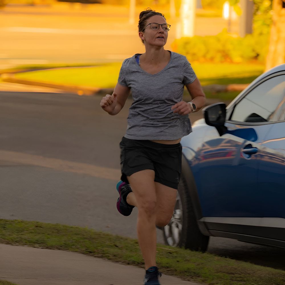 A Woman Is Running Down A Sidewalk Next To A Blue Car — Ultimate Results Training in Aitkenvale, QLD