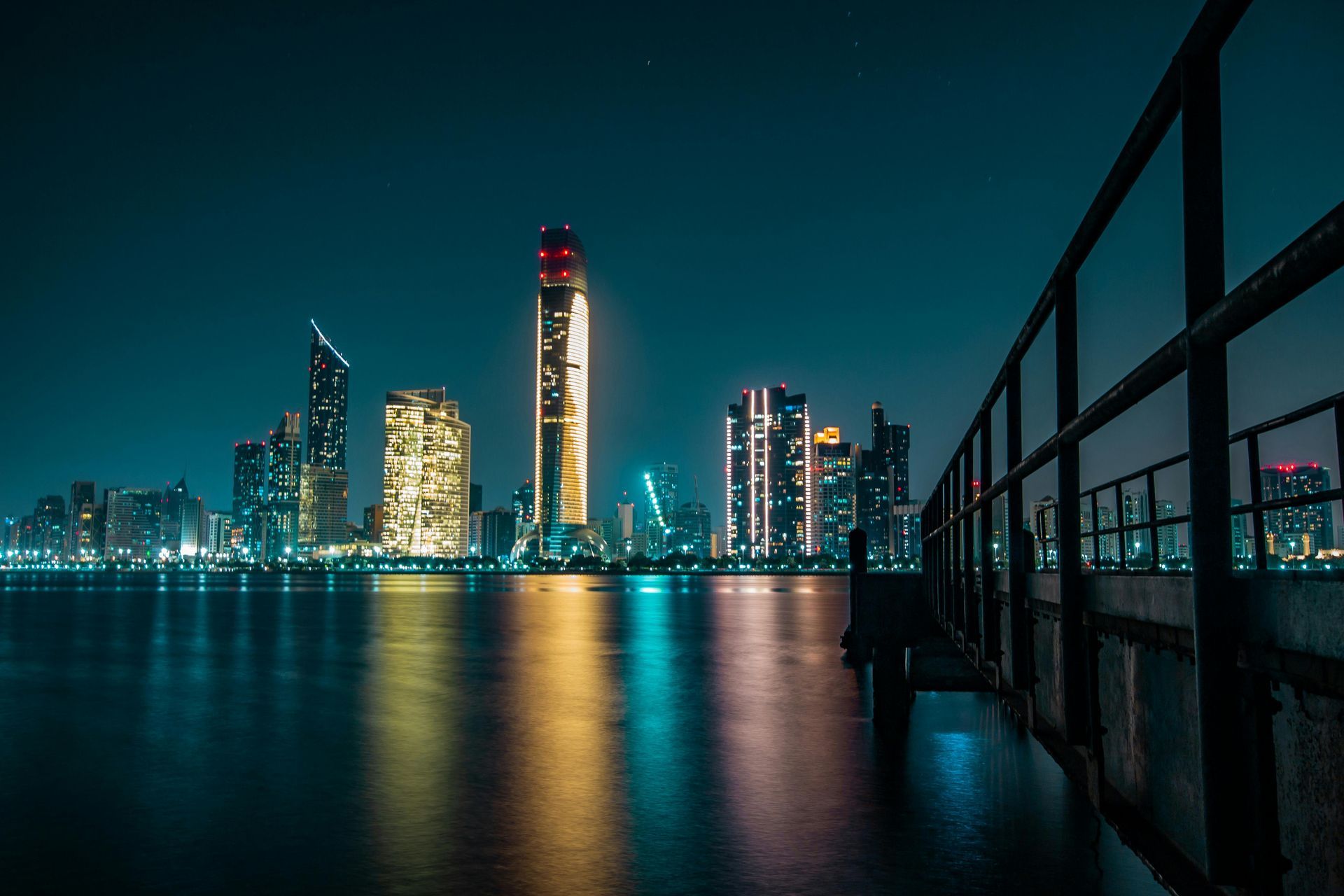 Night view of a distant city skyline glowing under a dark, hazy sky.