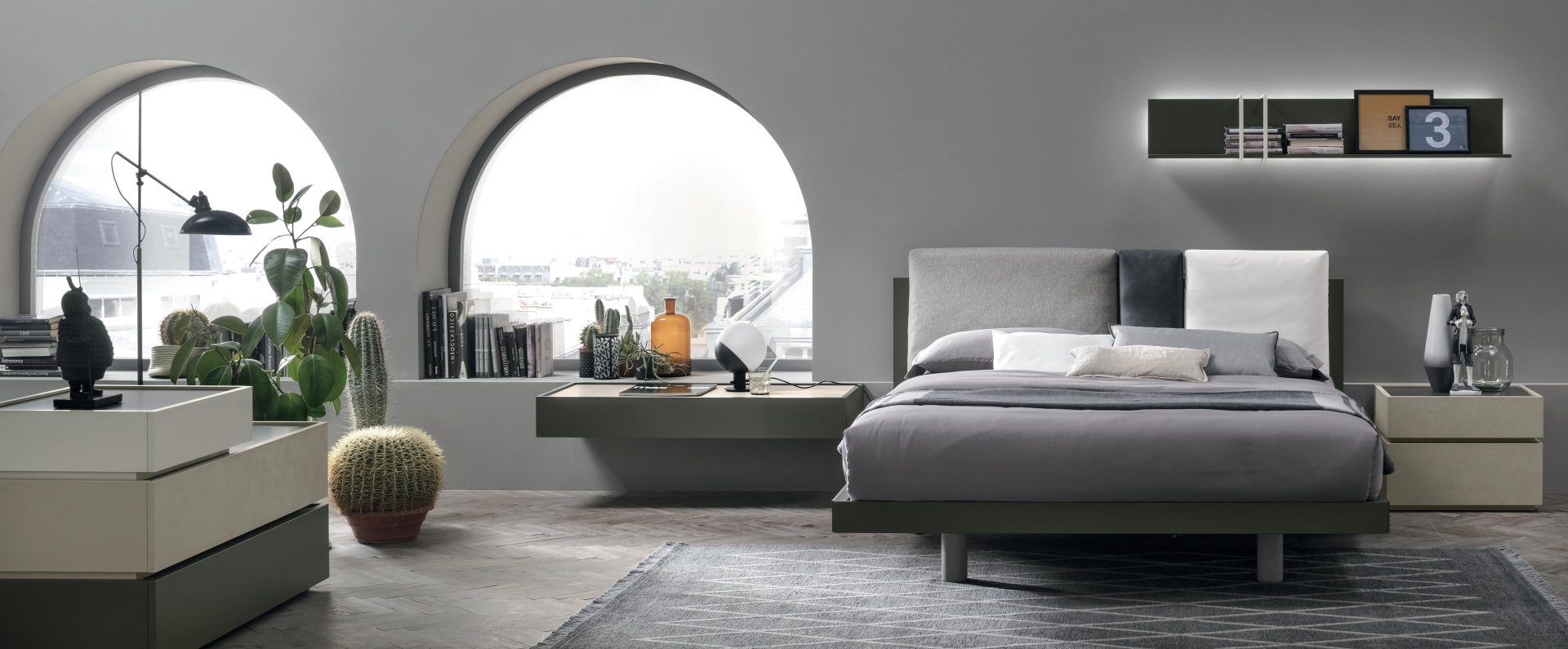 Una camera da letto con un letto, due comodini, uno scaffale e due finestre.