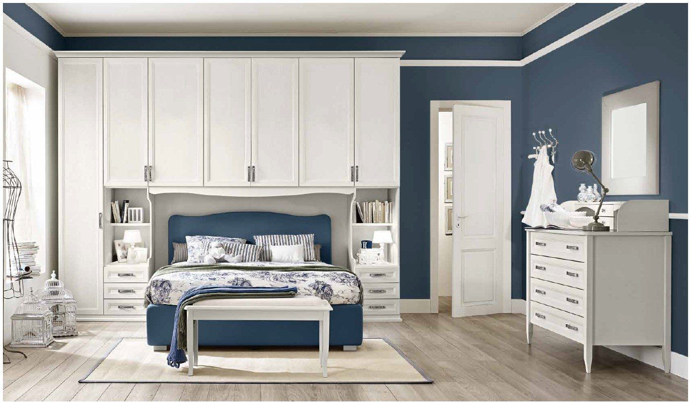 Una camera da letto con un letto, una cassettiera, uno specchio e pareti blu.