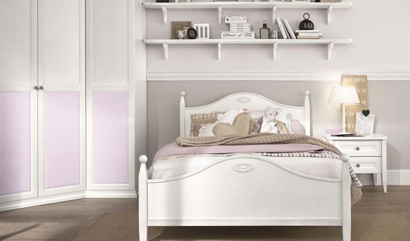 Una camera da letto con un letto bianco, un comodino e una mensola sopra il letto.