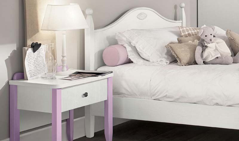 Una camera da letto con un letto, un comodino, una lampada e un orsacchiotto.