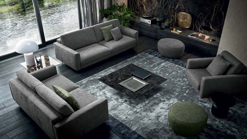 Un soggiorno con divano, sedia, tavolino e tappeto.