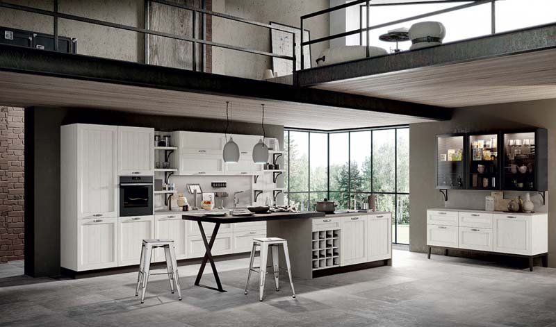 Una cucina con mobili bianchi, sgabelli, un tavolo e un balcone.