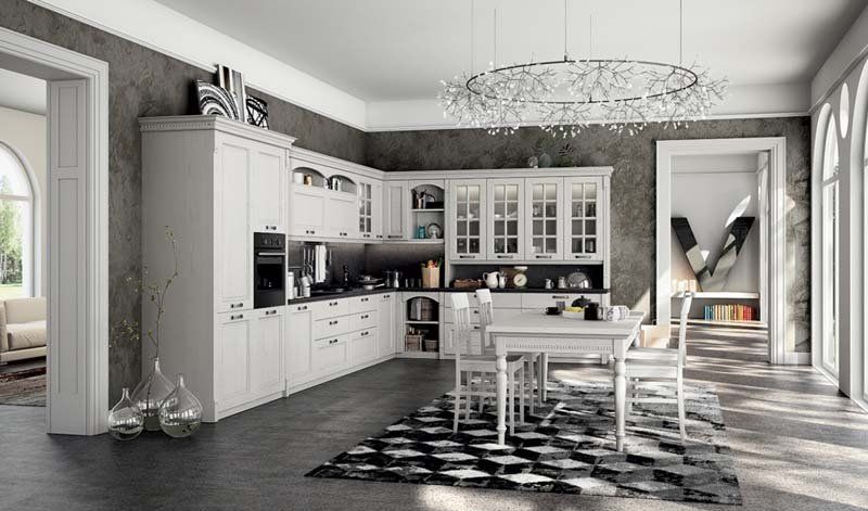 Una cucina con mobili bianchi, tavolo da pranzo e sedie.