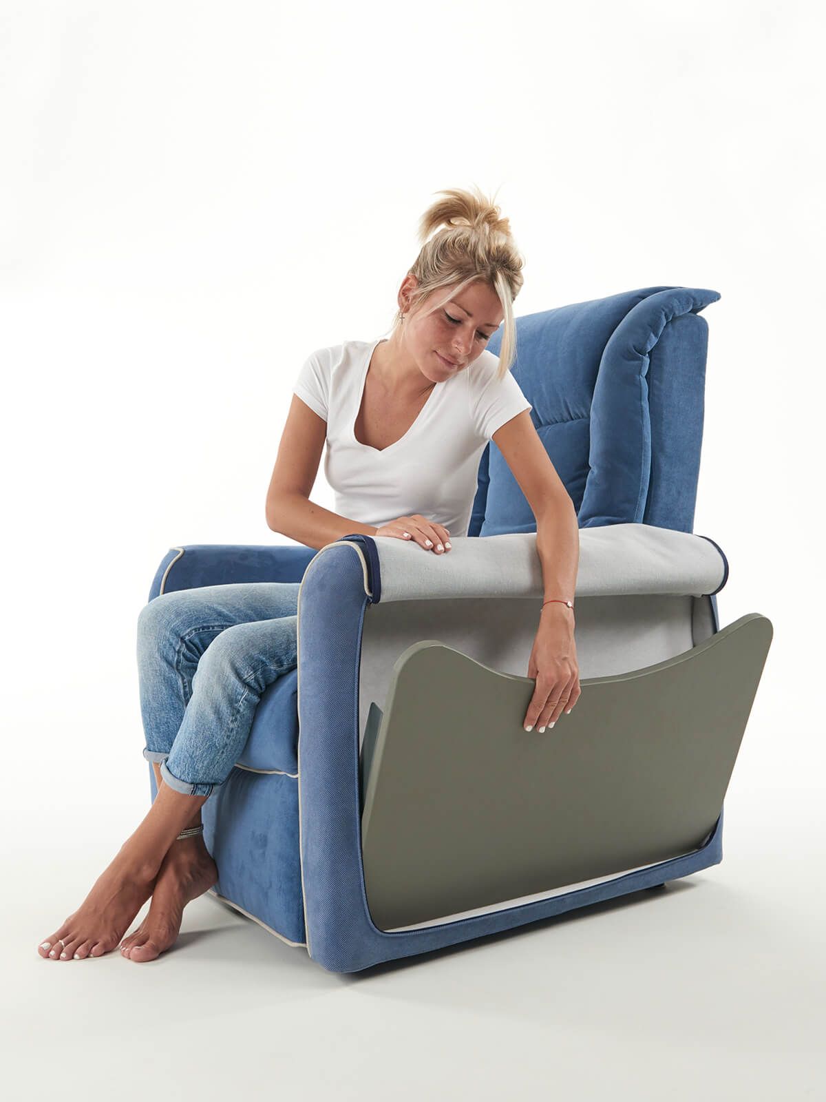 Una donna è seduta su una sedia blu con le gambe incrociate.