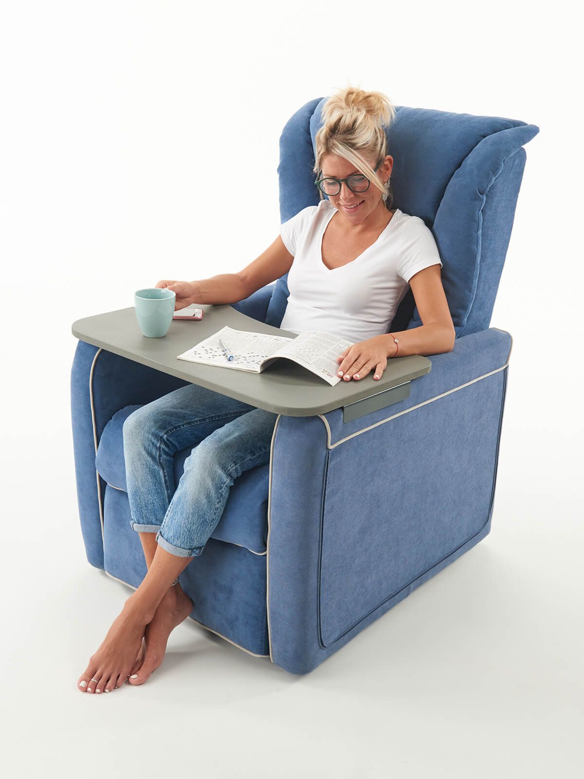 Una donna è seduta su una sedia blu e legge un libro.