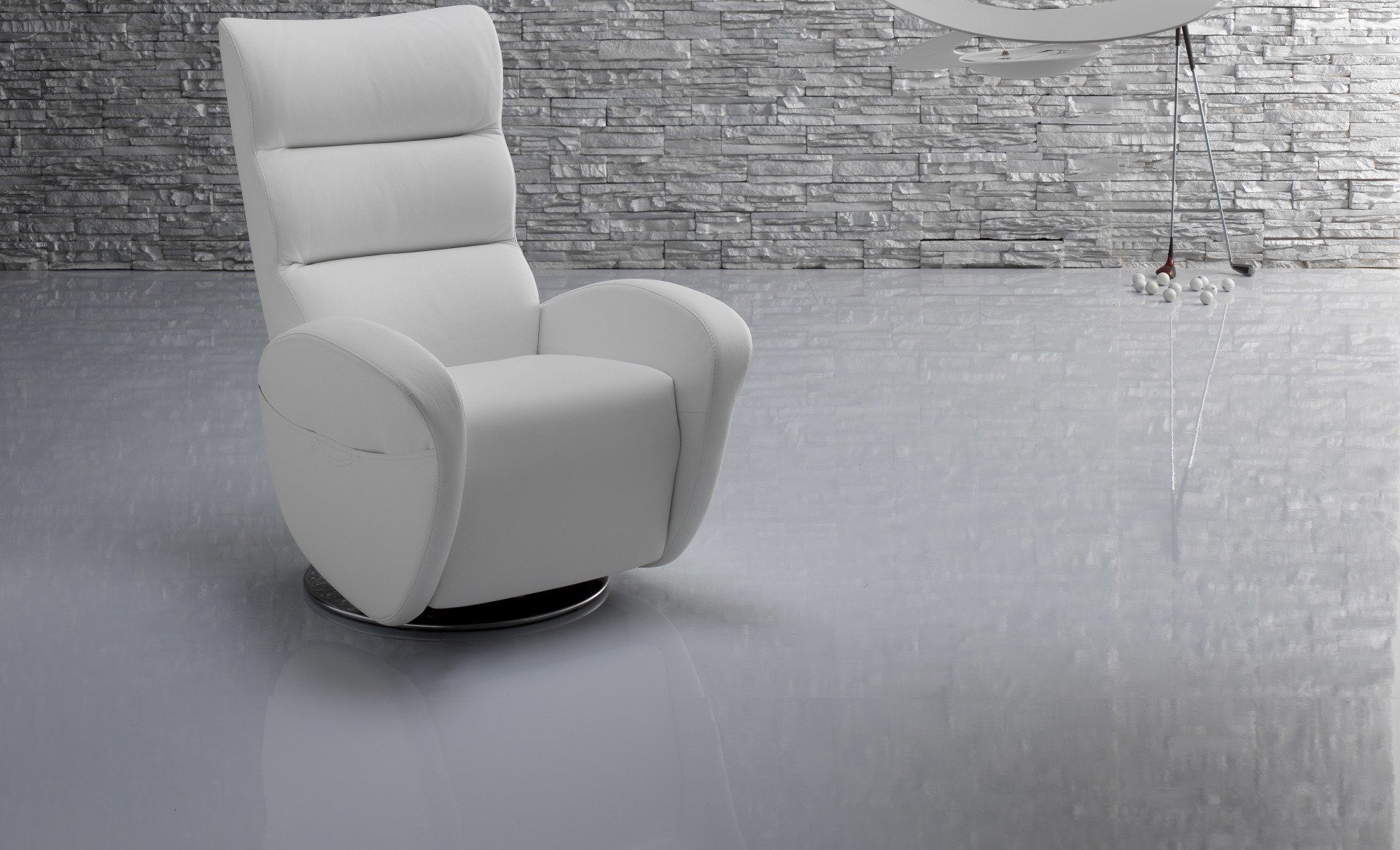 Una poltrona reclinabile bianca è posizionata davanti a un muro di mattoni.
