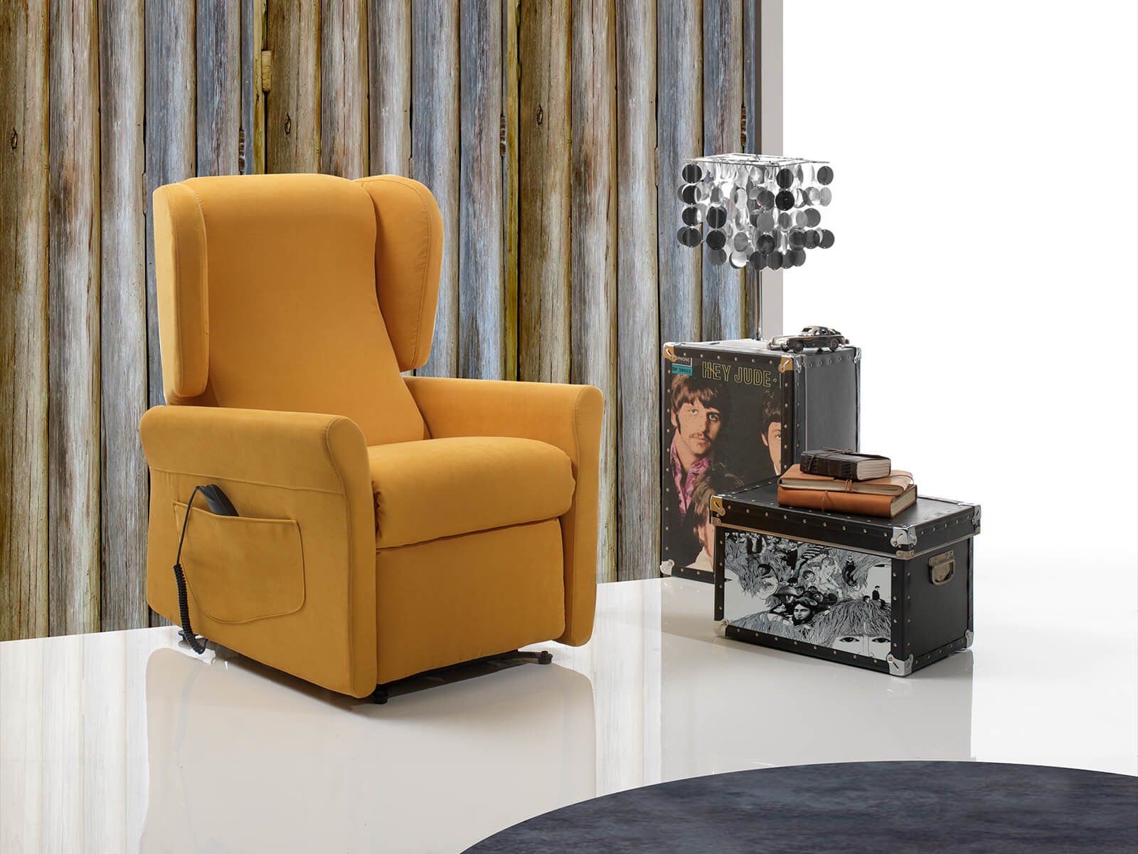 Una poltrona reclinabile gialla è posizionata in un soggiorno accanto a un baule.