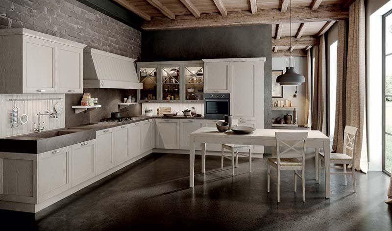 Una cucina con mobili bianchi, un tavolo e sedie.