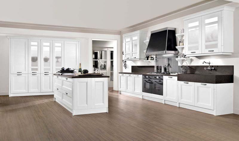 Una cucina con mobili bianchi, ripiani neri, un lavandino e un fornello.