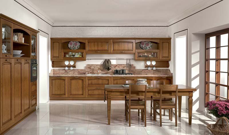 Una cucina con mobili in legno, tavolo e sedie