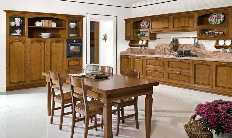 Una cucina con mobili in legno, tavolo e sedie