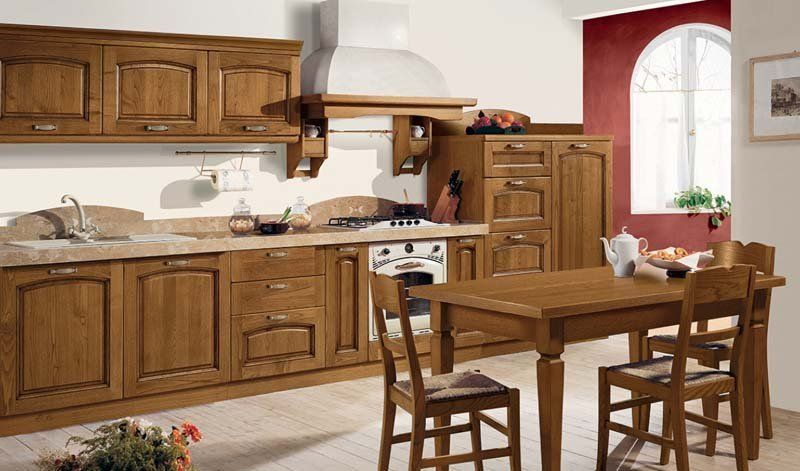 Una cucina con mobili in legno, tavolo e sedie