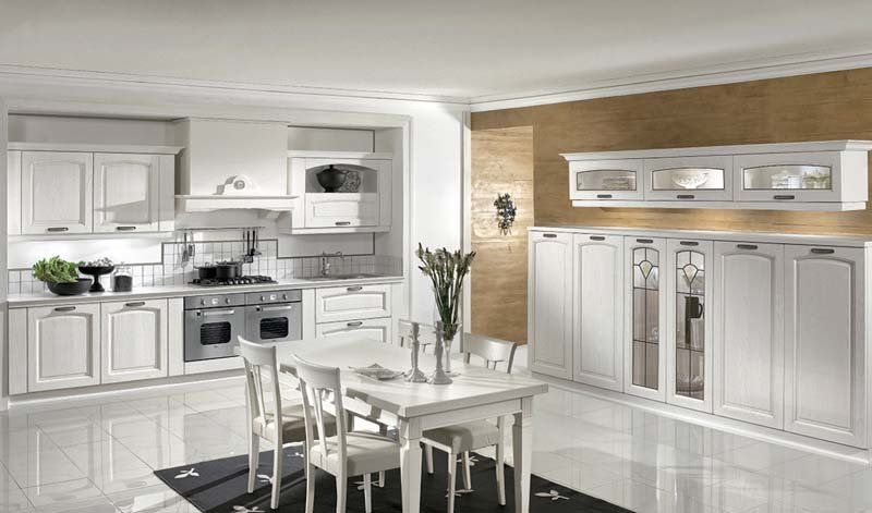 Una cucina con mobili bianchi, tavolo e sedie