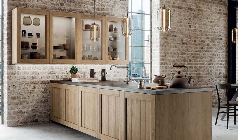 Una cucina con mobili in legno, un lavandino e un muro di mattoni.