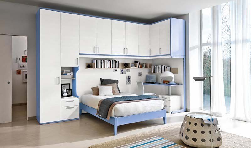 Una camera da letto con un letto blu e armadi bianchi