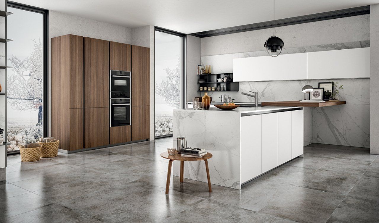 Una cucina con mobili bianchi e mobili in legno e una grande isola al centro.